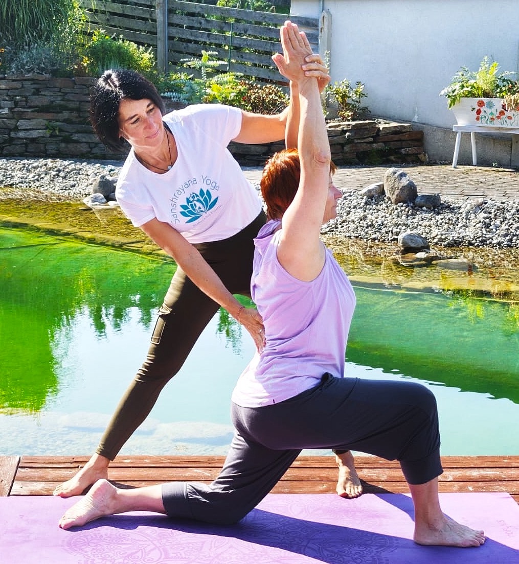 Zeigen Sie eine Einzel-Yogastunde mit einem Lehrer, der einen Schüler anleitet. Die Kulisse ist ein helles und luftiges Yogastudio. Der Fokus liegt auf der Verbindung zwischen Lehrer und Schüler.
